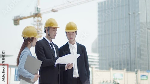 Architect And Inspector In Helmets With Documents Checking Plans At Construction Site. Contractor recheck drawing and solve building structure problems. photo