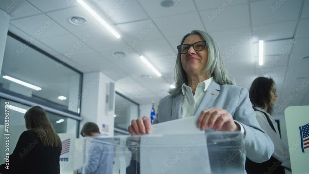 American businesswoman puts ballot in box. Press takes photo of woman after voting. Diverse US citizens vote in booths at polling station. Elections Day in the United States of America. Democracy. American businesswoman puts ballot in box. Press takes photo of woman after voting. Diverse US citizens vote in booths at polling station. Elections Day in the United States of America. Democracy.
