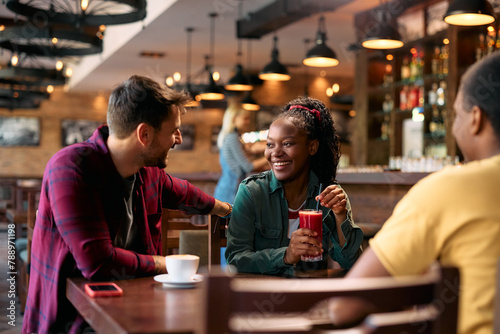 Happy black woman talking to her friends in pub.