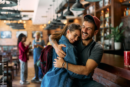 Young happy couple embracing while meeting in pub.