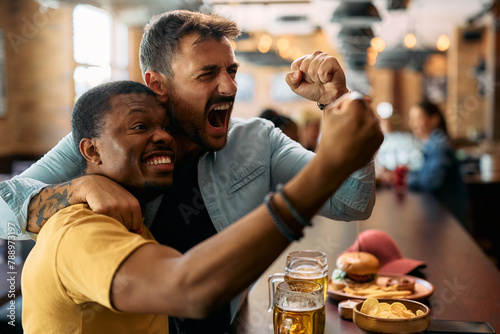 Bilde på lerret Excited men cheering while watching watching sports game on TV in  bar