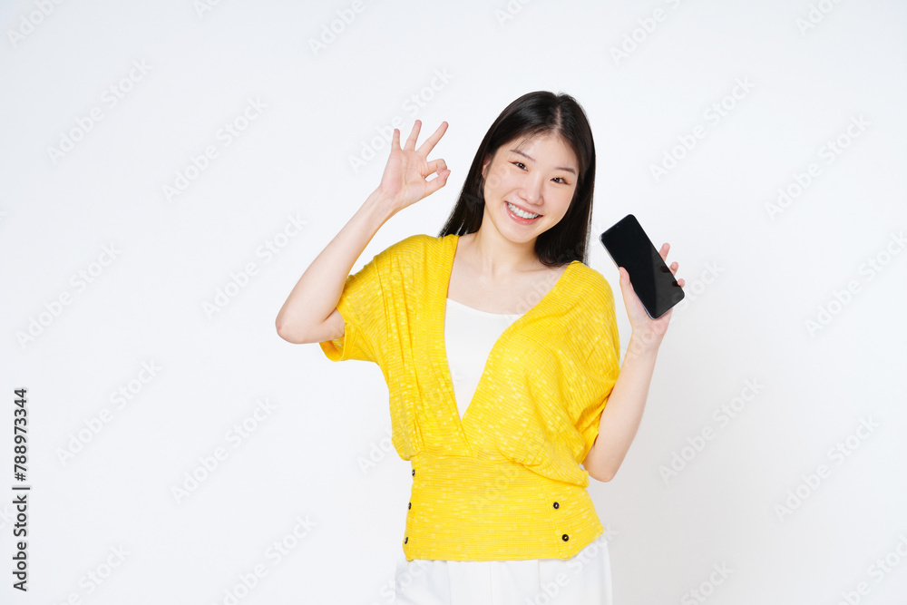Young asian woman holding smartphone and shows OK sign on white background. Young asian woman holding smartphone and shows OK sign on white background.