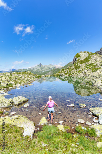 A little girl enters a mountain lake with her feet