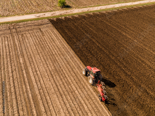 Tractor preparing the land for planting in vast agricultural fields, captured from above