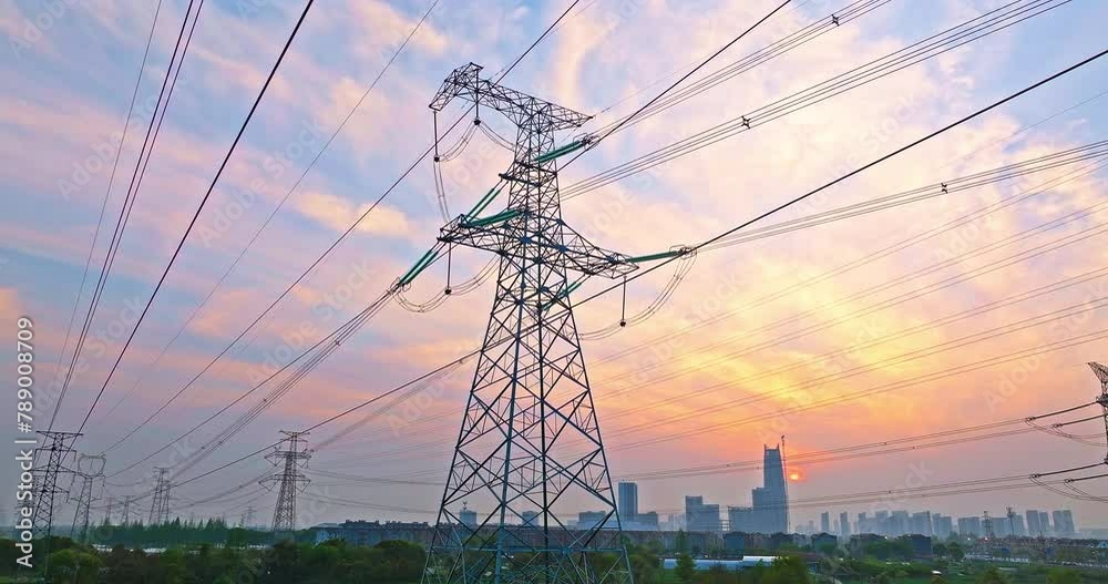 Aerial view of high voltage electricity towers and city skyline at sunset