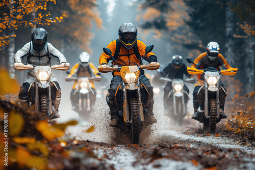 male motorcycle racers on sports enduro motorcycles compete in an off-road race riding on muddy road in forest photo