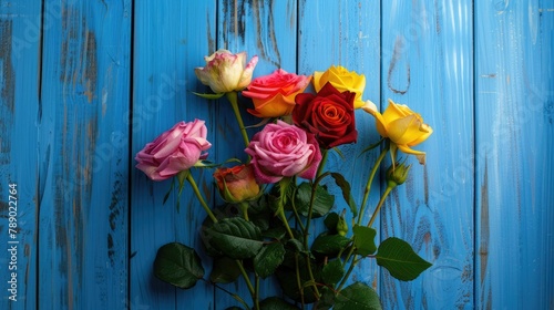 A vibrant bouquet of multicolored roses blooms against a rustic blue wooden backdrop