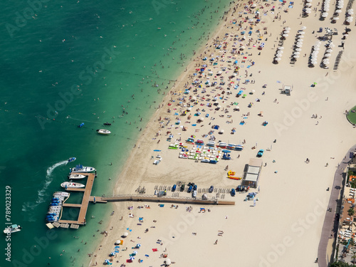 aerial landscape view of Marina Beach near Jumeirah Beach Residence area with parasols, many people on the beach and in water, Watersport activities  