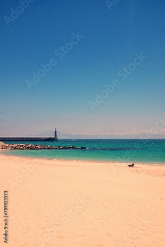 Atlantic ocean and beach with golden sand and blue sky in Tarifa, Spain. Playa de Bolonia on Atlantic coast of Tarifa, Province of Cadiz, Andalucia, southern Spain. Waves on Levante wind on summer day