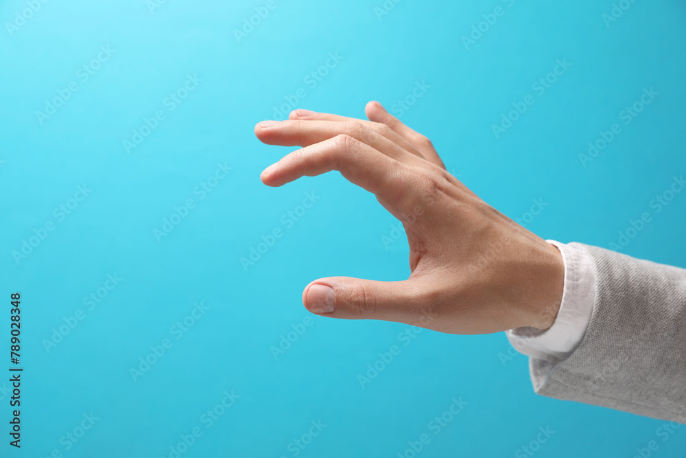 Man holding something in hand on light blue background, closeup. Space for text Man holding something in hand on light blue background, closeup. Space for text