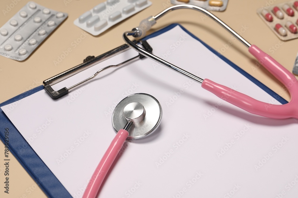 Stethoscope, clipboard and pills on beige background, closeup. Medical tool Stethoscope, clipboard and pills on beige background, closeup. Medical tool