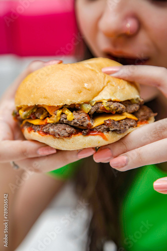 Closeup of a female having double smashed beef donut burger in a cafe restaurant.