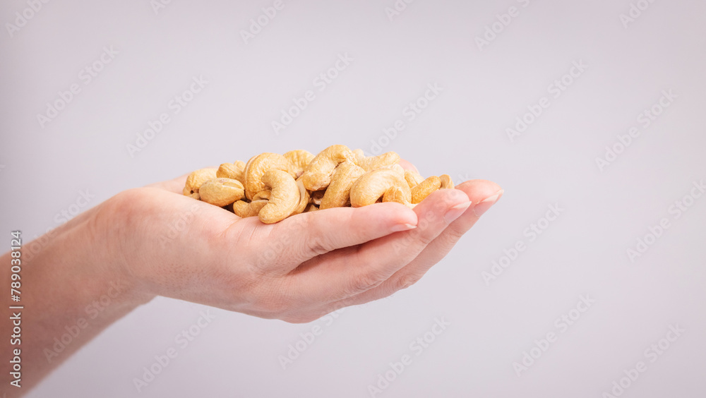 cashew nuts in female hands on a light background. cashew nuts in female hands on a light background.