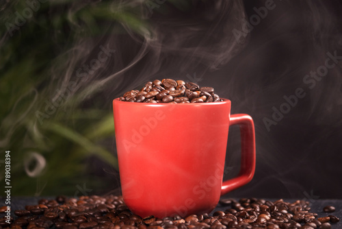 many macro aromatic coffee beans in a red cup on a dark background.