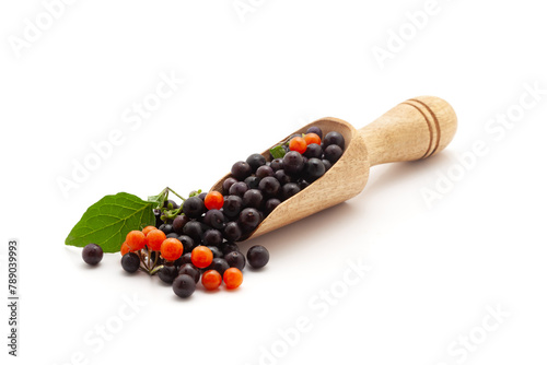 Front view of a wooden scoop filled with Fresh Organic Black and Red nightshade or Makoy (Solanum nigrum) fruit. Isolated on a white background. photo