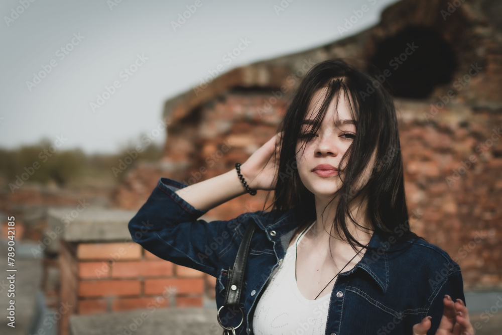 A young girl walks in the park near the old fortress - obrazy, fototapety, plakaty 