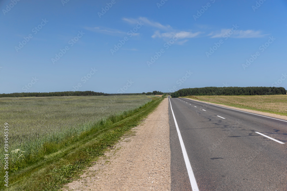 paved narrow road in a straight line through the field paved narrow road in a straight line through the field
