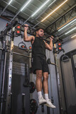 Intense workout scene as a fit Asian man engages in behind the neck pull-ups at a well-equipped gym, showcasing strength and dedication.
