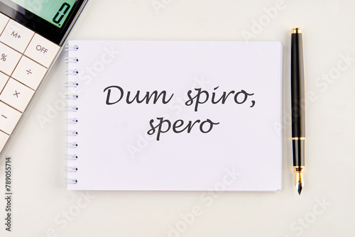 Dum Spiro Spero - latin phrase means While I Breath, I Hope. on a white notebook photo