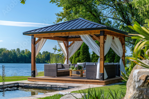 Luxurious gazebo with white curtains on lake shore in sunlight