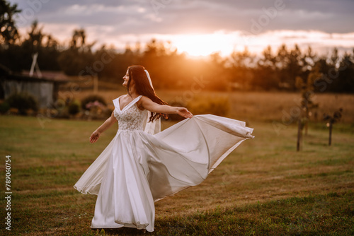 Valmiera, Latvia- July 28, 2023 - A joyful bride twirling in her wedding dress outdoors with a sunset backdrop.