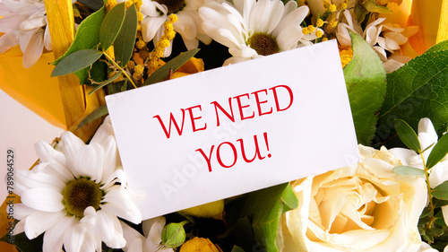 WE NEED YOU Message written on a business card on a background of flowers
