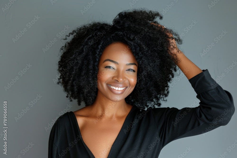 A black woman with curly, wavy hair and a grey studio background smiles and is confident. African American girl takes care of her body for natural beauty, health, and radiance. A black woman with curly, wavy hair and a grey studio background smiles and is confident. African American girl takes care of her body for natural beauty, health, and radiance.