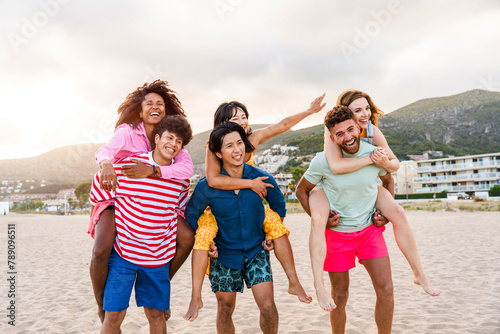 Group of young best friends bonding outdoors at seaside - Multiethnic young cheerful people hanging out at the beach