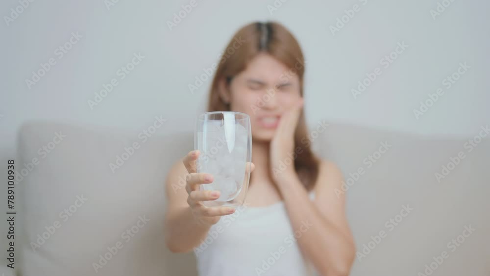 Teeth Sensitive to Cold concept. woman hold Ice Water glass and having toothache and pain after eat. Tooth Decay or Gum Disease, Grinding Teeth and Stress, Exposed Nerve Roots, Crack and Receding Gums Teeth Sensitive to Cold concept. woman hold Ice Water glass and having toothache and pain after eat. Tooth Decay or Gum Disease, Grinding Teeth and Stress, Exposed Nerve Roots, Crack and Receding Gums