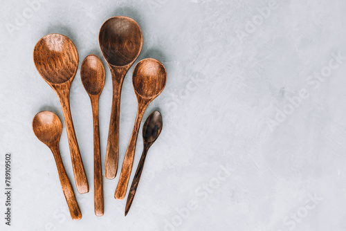 Wooden spoons. Wooden spoons on gray stone background, kitchen concept. © nblxer