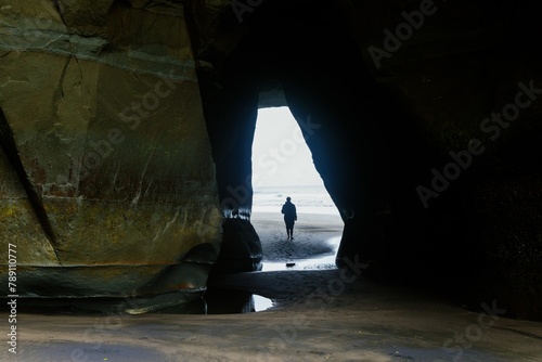 Lone person walking through a hle in the rock at the Three Sisters, Tongaporutu, Taranaki, New Zealand. photo