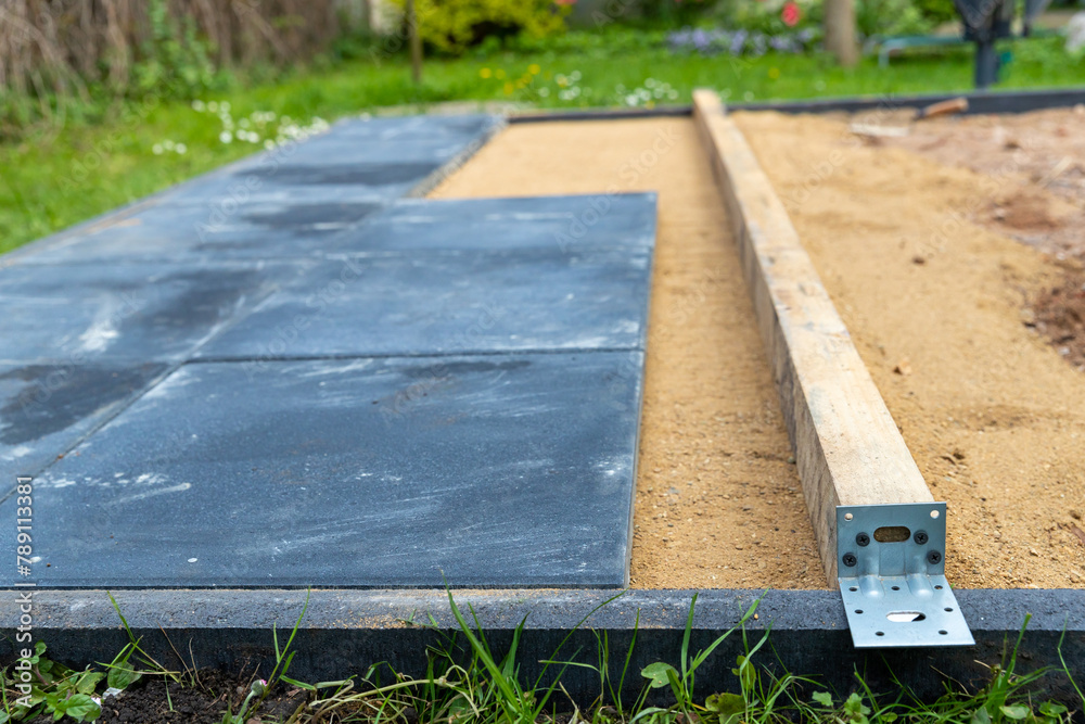 Sand als Unterbau gerade abziehen um Gehwegplatten darauf zu verlegen