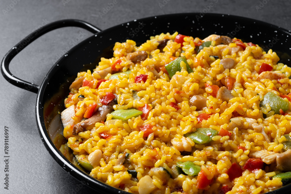 Yellow rice with chicken and vegetables on black slate background. Close up Yellow rice with chicken and vegetables on black slate background. Close up