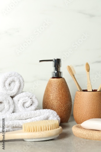 Different bath accessories and personal care products on gray table near white marble wall