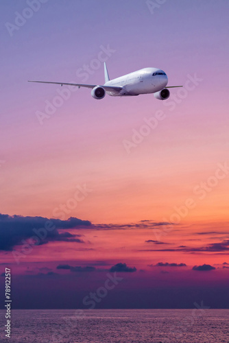 Wide body passenger airliner is landing over the sea against the backdrop of scenic sunrise sky