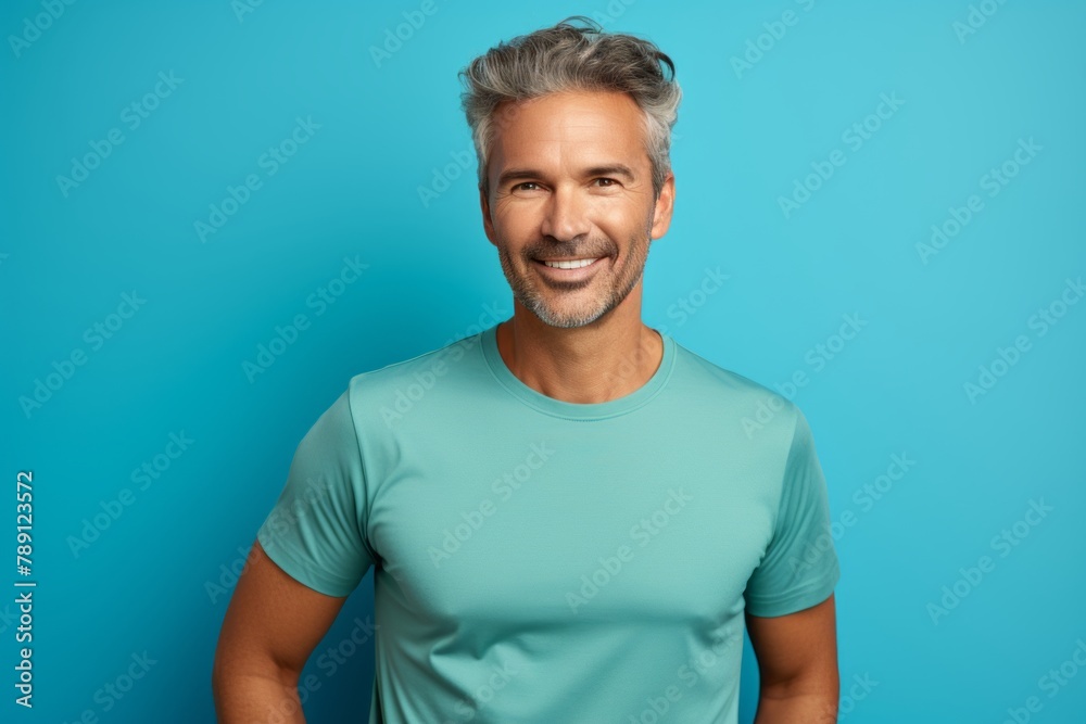Portrait of a cheerful man in his 40s wearing a moisture-wicking running shirt while standing against solid color backdrop Portrait of a cheerful man in his 40s wearing a moisture-wicking running shirt while standing against solid color backdrop