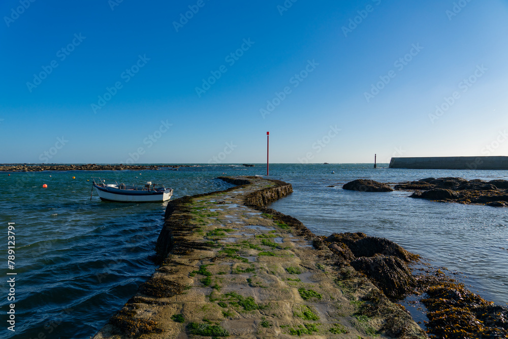 Une barque solitaire amarrée au pied de la jetée, témoignant du calme qui règne à Penmarc'h, Finistère.