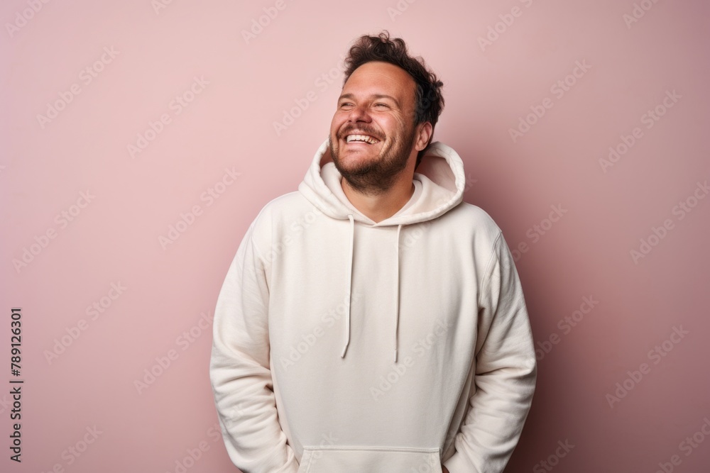 Portrait of a happy man in his 30s sporting a comfortable hoodie over solid pastel color wall Portrait of a happy man in his 30s sporting a comfortable hoodie over solid pastel color wall