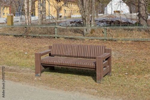 Brown wooden park bench in spring.
