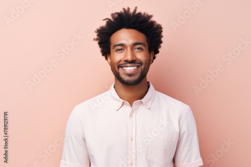 Portrait of a satisfied afro-american man in his 20s wearing a simple cotton shirt while standing against solid pastel color wall