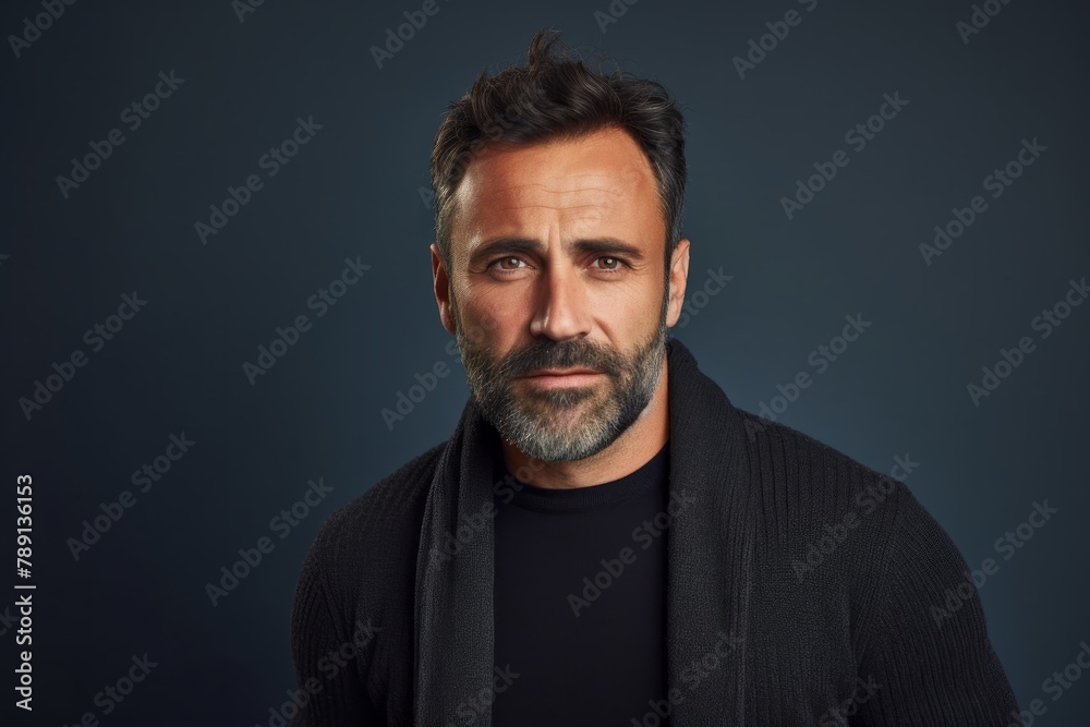 Portrait of a content man in his 40s wearing a chic cardigan over blank studio backdrop