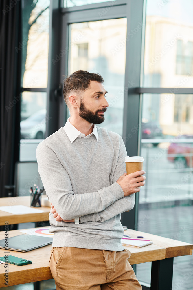 A man is seated at a table, quietly enjoying a cup of coffee in a modern office setting. A man is seated at a table, quietly enjoying a cup of coffee in a modern office setting.