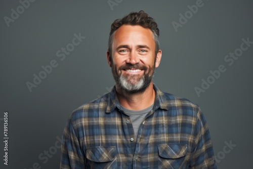 Portrait of a satisfied man in his 40s wearing a comfy flannel shirt isolated on blank studio backdrop