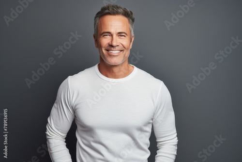 Portrait of a smiling man in his 50s sporting a long-sleeved thermal undershirt in blank studio backdrop