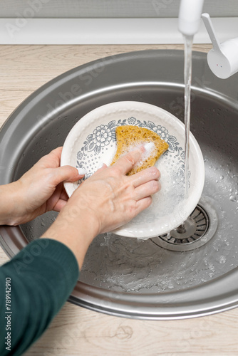  housewife washes a plate in the kitchen sink. photo