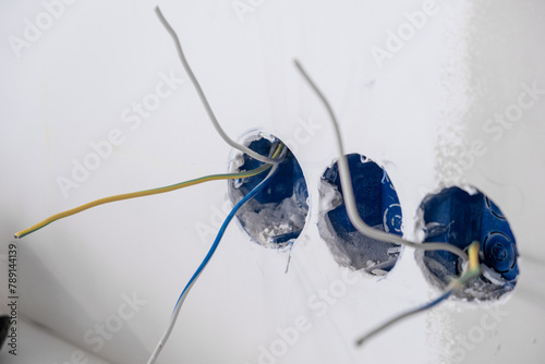 Apartment renovation. Electrical wiring. Wires sticking out of the wall. Wiring electrical cables on wall in the apartment Unfinished electrical mains outlet socket with electrical wires.