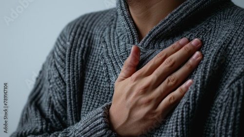 Detailed shot of a hand over the chest area to depict heart pain or chest tightness, against a simple white backdrop.