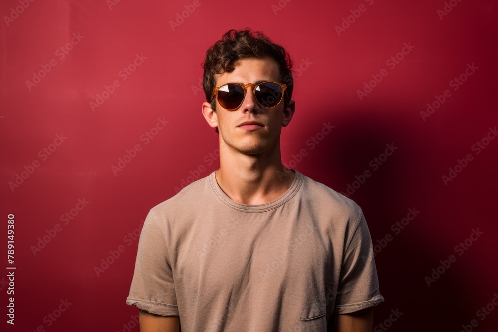 Portrait of a glad man in his 20s wearing a trendy sunglasses over plain cyclorama studio wall Portrait of a glad man in his 20s wearing a trendy sunglasses over plain cyclorama studio wall