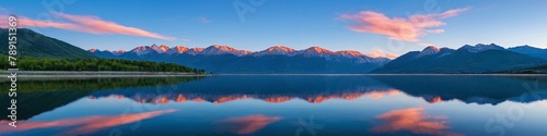 Majestic peaks reflected in a calm lake at sunset. Dawn in the mountains. Panoramic view of the beautiful mountain landscape.