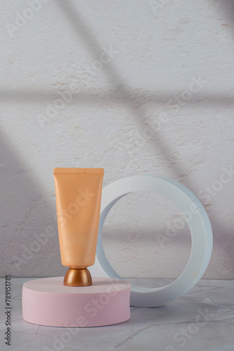 Cosmetic cream tube in womans hand on placement background with palm shadow. Beauty concept